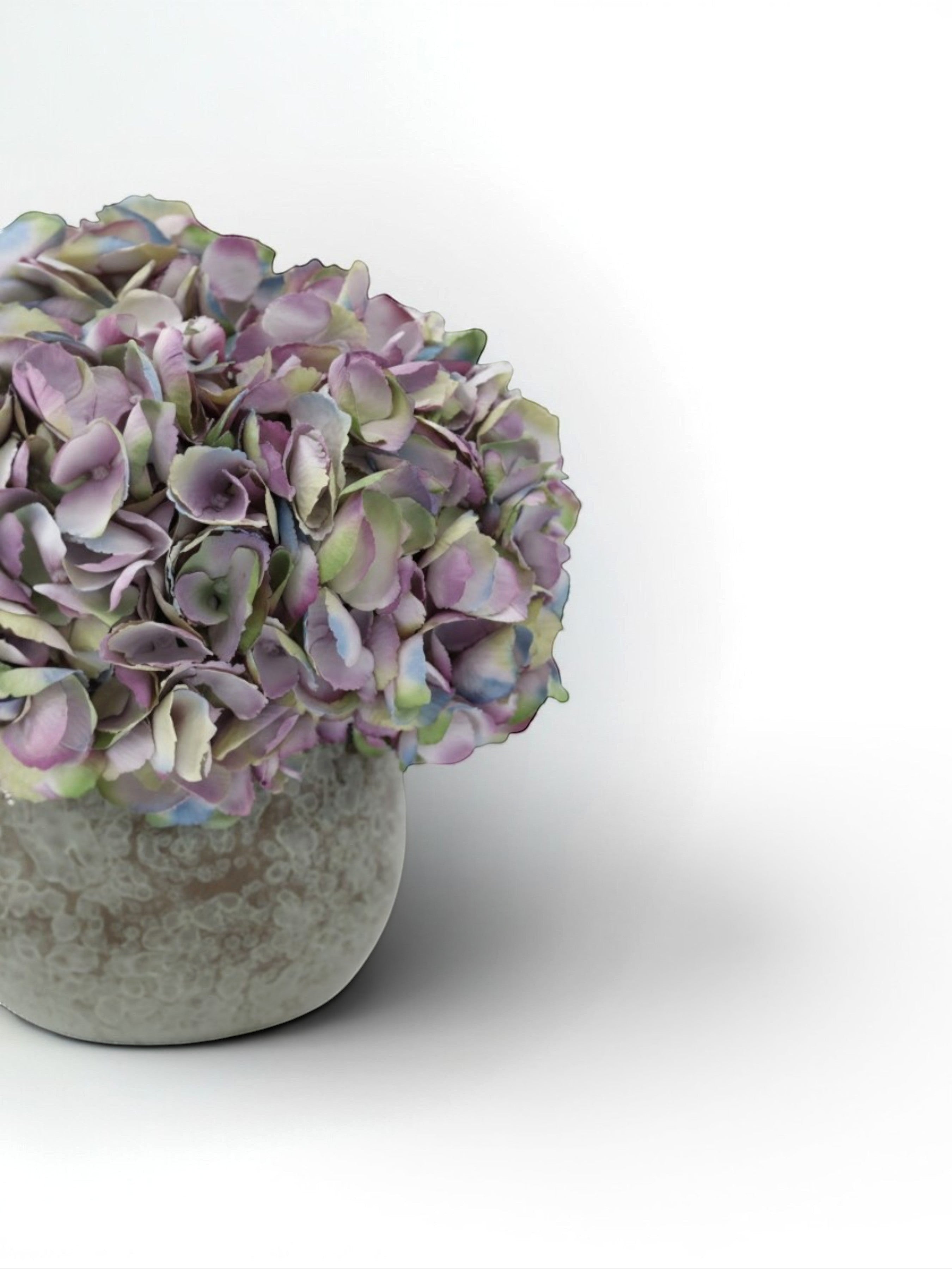 Sixty3 Styled faux hydrangea arrangement in dusty lavender, sage, and ink colors in a textured stone vessel.