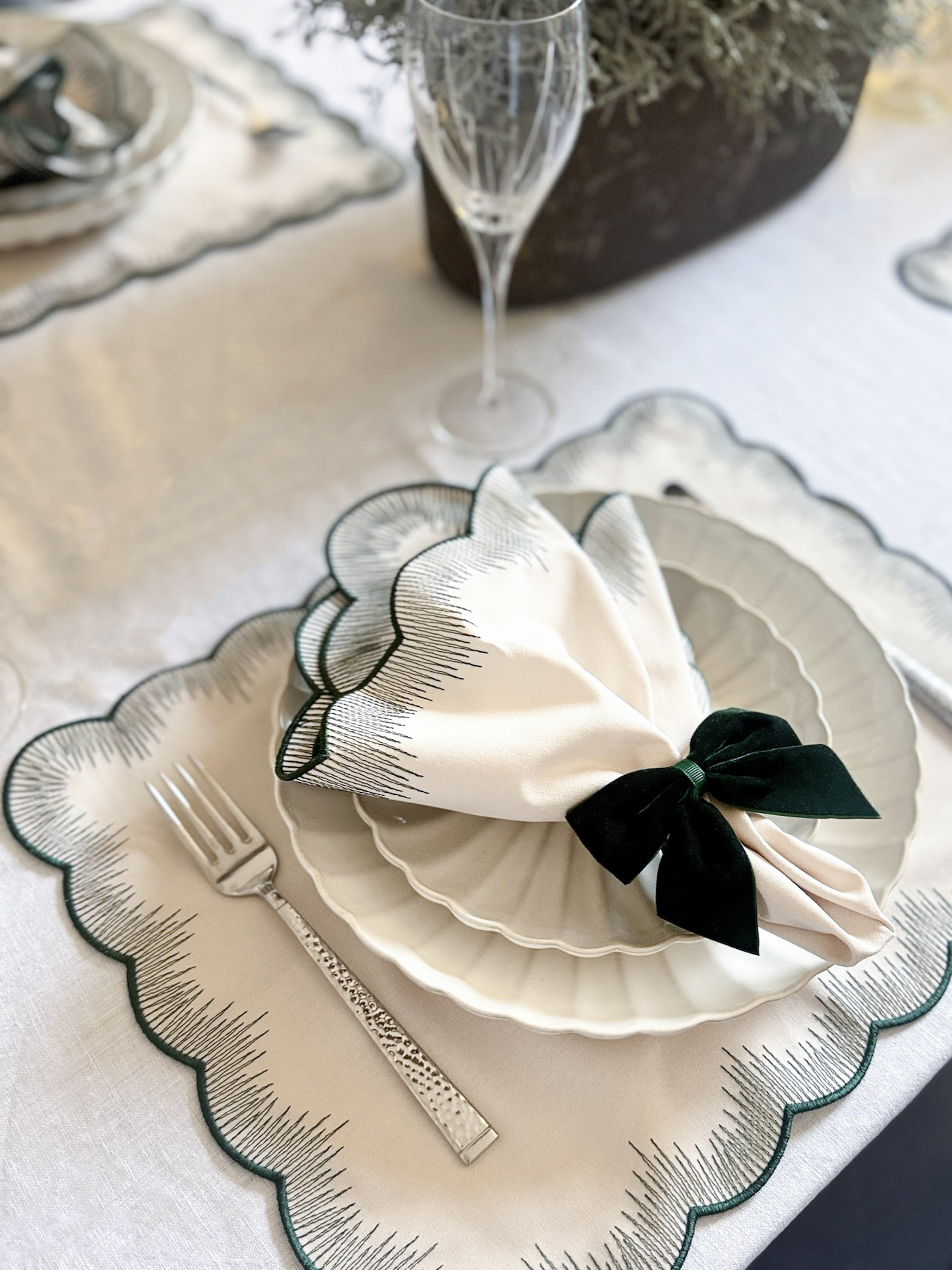 Beige napkins with forest green embroidered edges and matching placemats and napkin bows