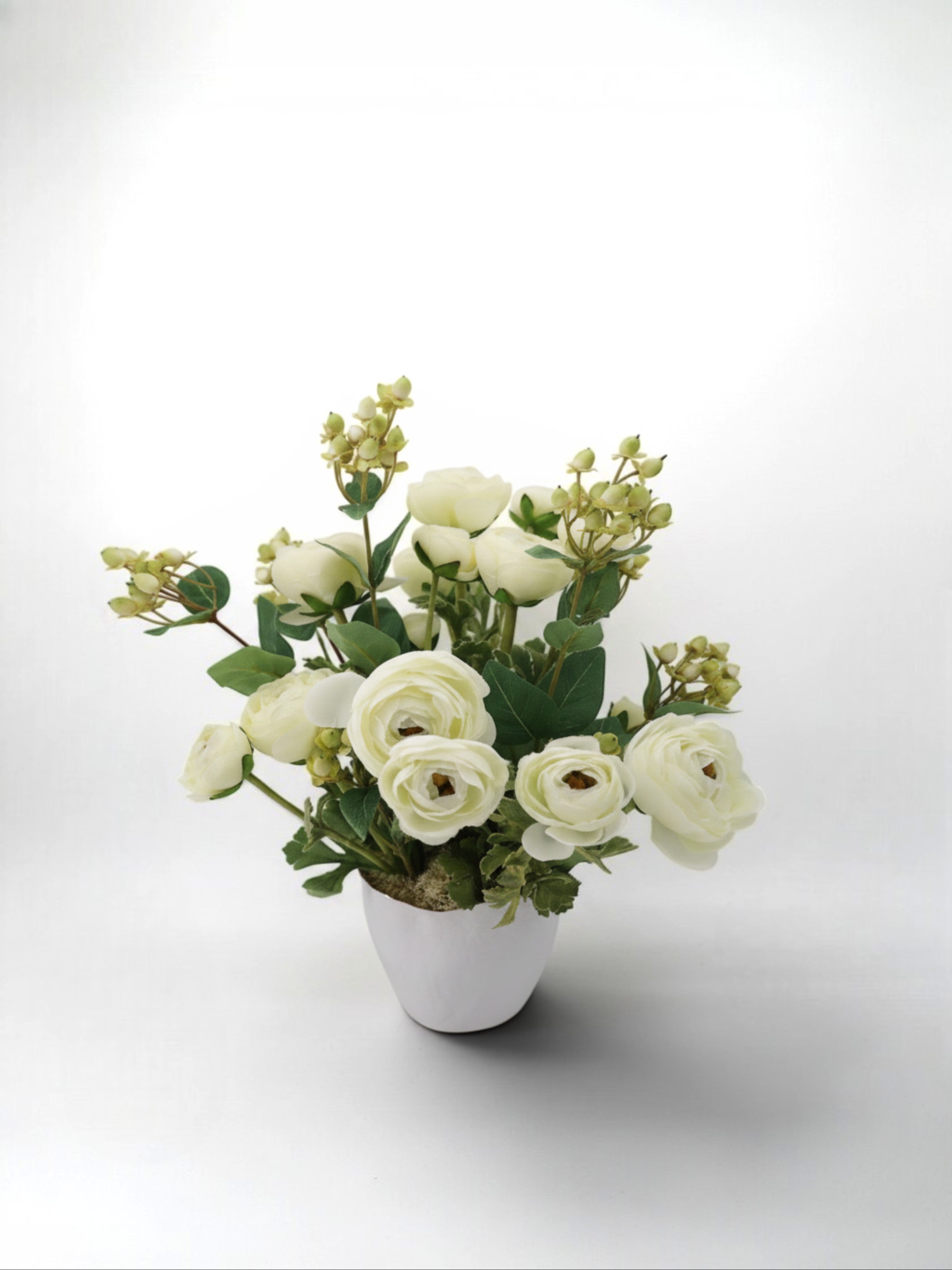 Sixty3 Styled cream ranunculus artificial floral arrangement in a white pot with green foliage and berries.
